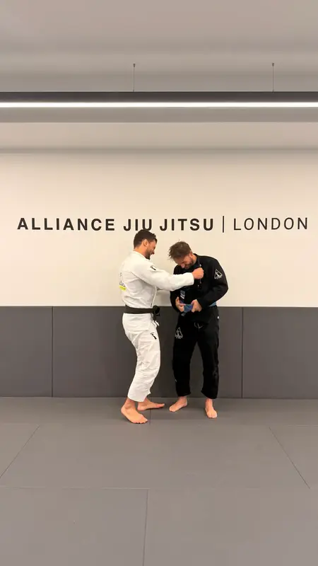 A coach and a student in gis on the mat at Alliance Jiu Jitsu London