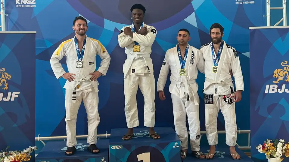 Four jiu-jitsu athletes in white gis with their medals on the podium at the IBJJF London International Open
