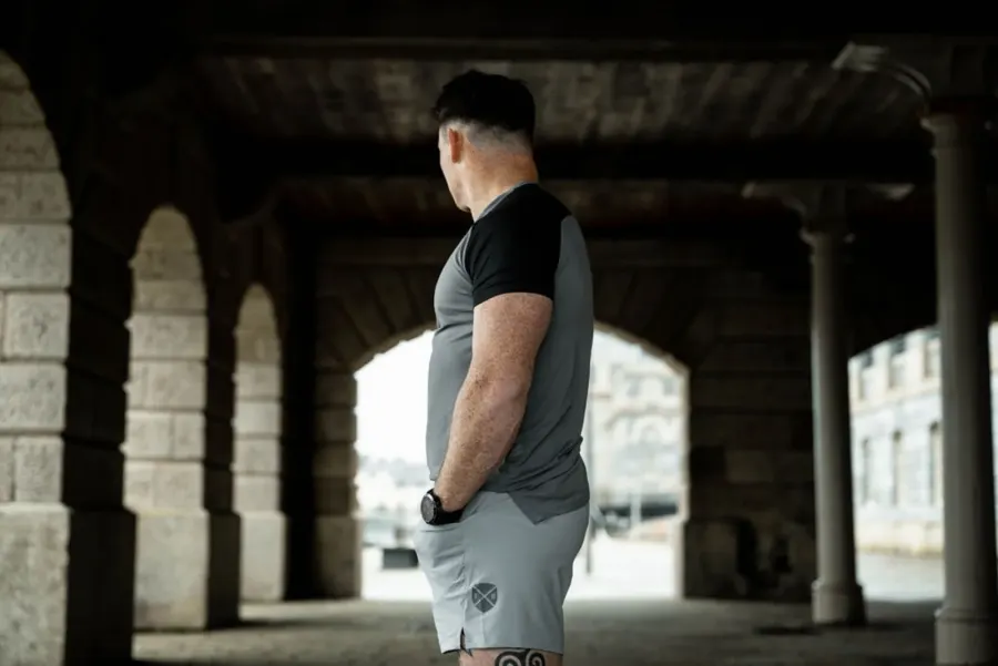 A man in training kit standing under stone arches